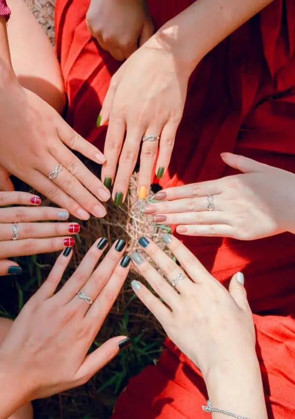 A vibrant top view of women showcasing painted nails and rings, emphasizing friendship and togetherness.