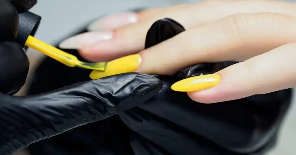 Closeup of a beautician applying yellow nail polish, showcasing precision and care.