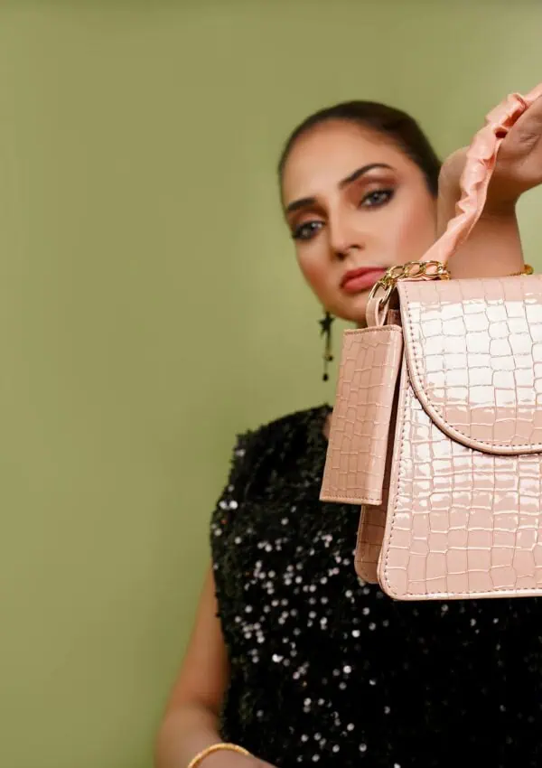 Woman holding a stylish pink leather handbag with croc texture, emphasizing elegance and fashion.