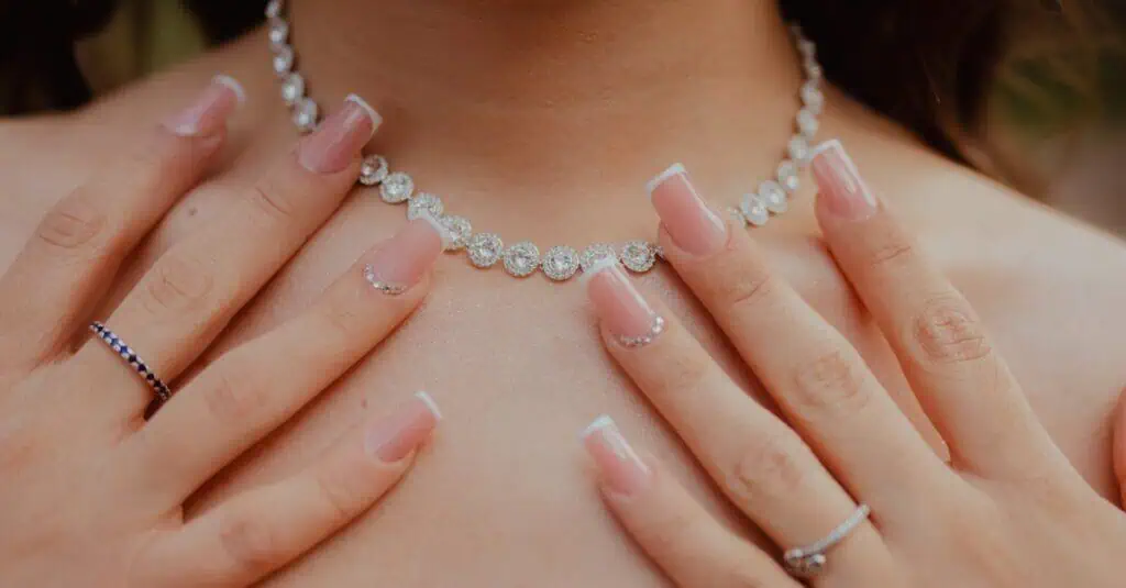 Close-up of elegant diamond necklace and manicured hands, showcasing jewelry fashion and style.