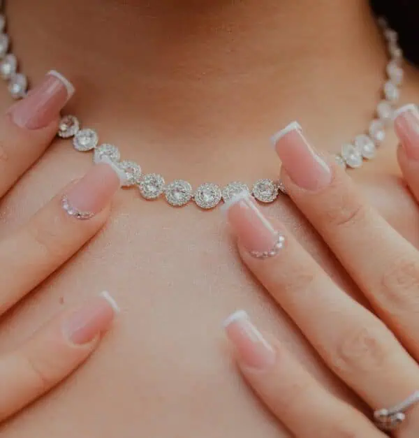 Close-up of elegant diamond necklace and manicured hands, showcasing jewelry fashion and style.