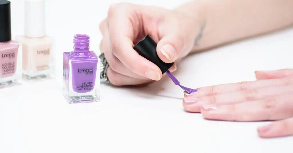 A close-up of a person applying purple nail polish as part of a manicure.
