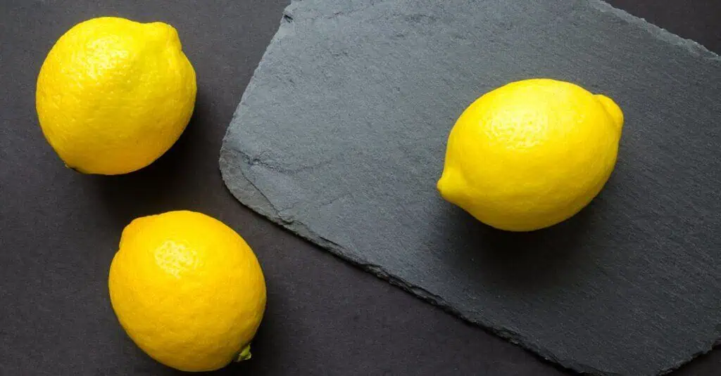 High-angle shot of vibrant lemons on dark slate, emphasizing freshness.