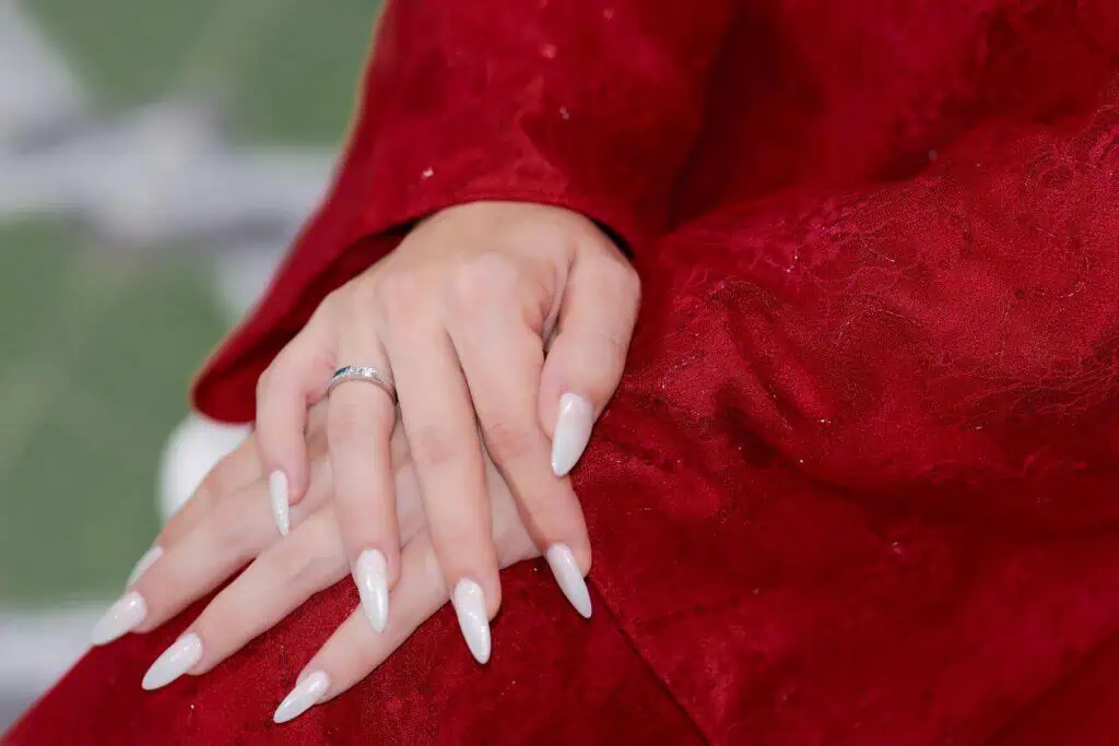 Close-up of manicured hands with long nails on red fabric. Elegant and stylish.