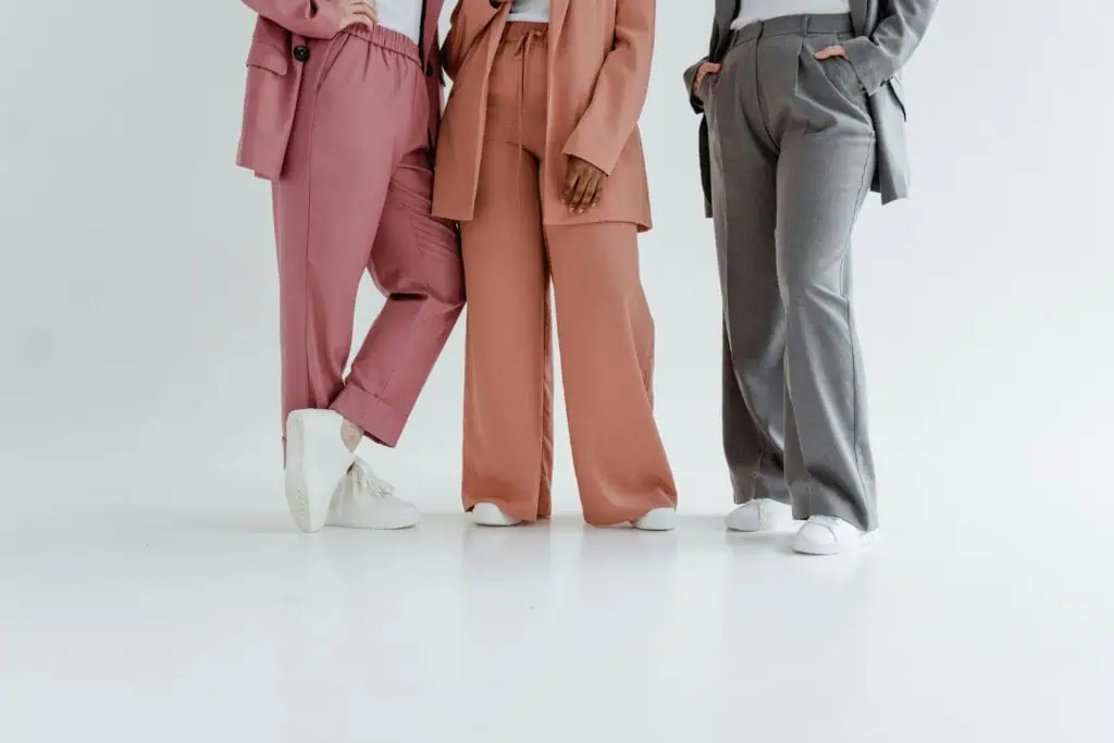 Stylish group of adults showcasing colorful trousers in a minimalist setting.