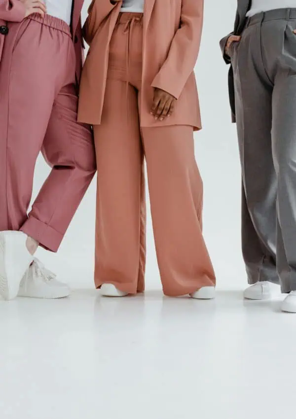 Stylish group of adults showcasing colorful trousers in a minimalist setting.