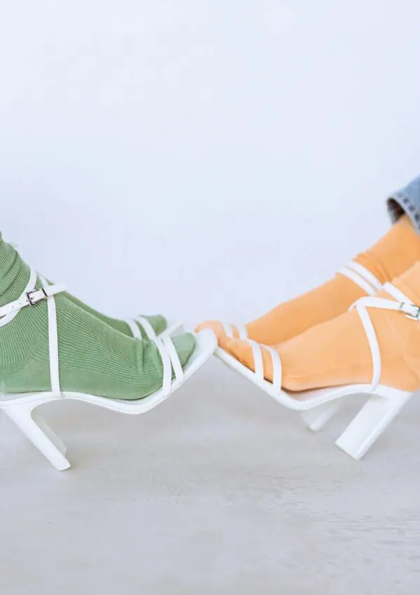 Trendy fashion shot of vibrant socks with white high heels in a studio setting.