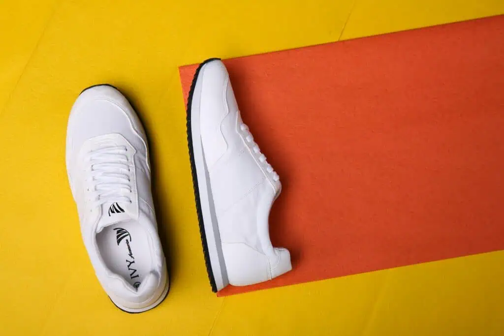 White sneakers displayed on a colorful orange and yellow background, highlighting modern fashion style.